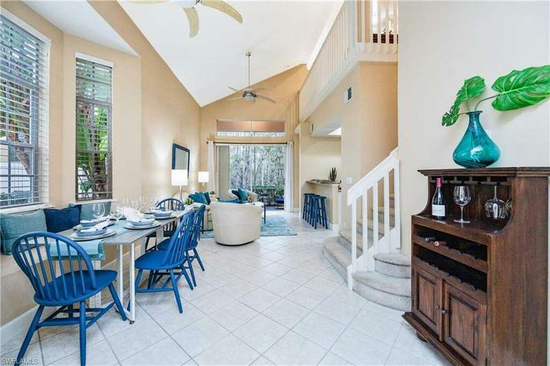 Dining room with light tile patterned flooring, ceiling fan, and high vaulted ceiling