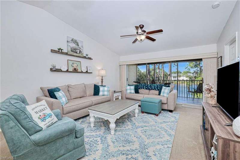 Carpeted living room featuring ceiling fan and lofted ceiling