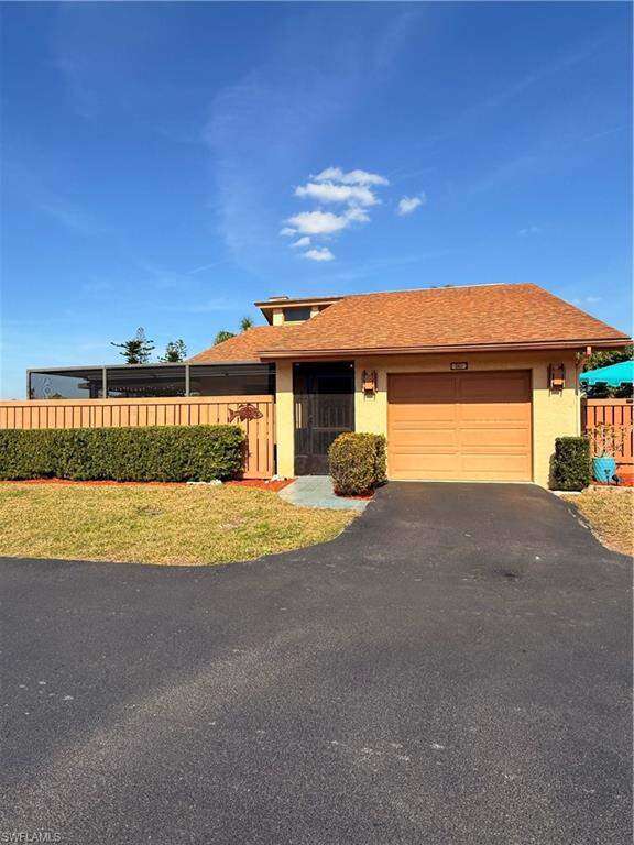 View of front of property featuring a garage, driveway, a fenced front yard, and stucco siding