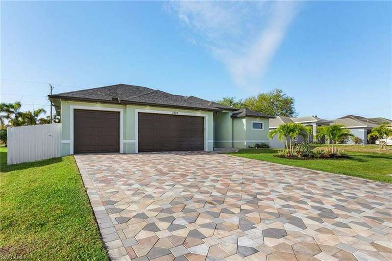 View of front of property with a front yard, decorative driveway, an attached garage, and stucco siding