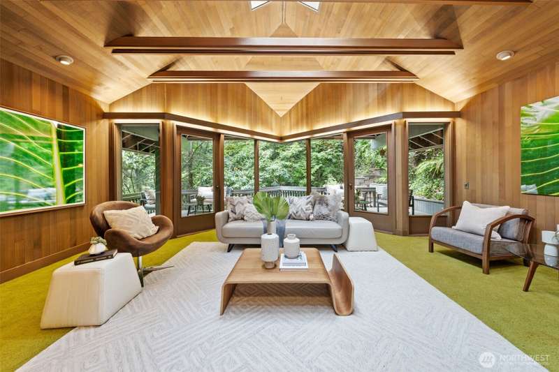 Stunning living room wrapped in rich cedar boards, where soaring ceilings and walls of windows bring the natural beauty of the outdoors inside—creating a warm, luxurious retreat.