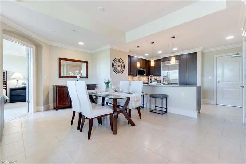 Kitchen with stainless steel appliances, dark brown cabinetry, backsplash, ornamental molding, and light stone counters
