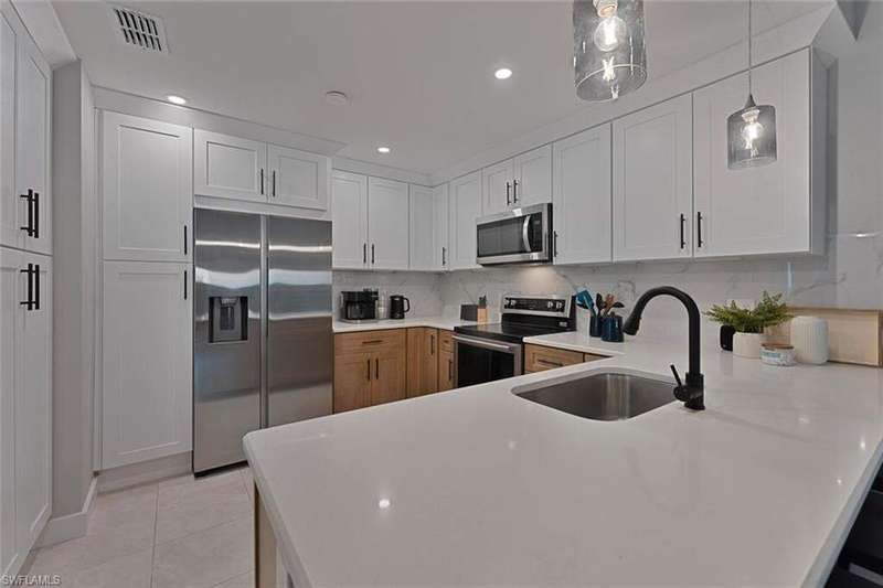 Kitchen with a sink, tasteful backsplash, a peninsula, light tile patterned floors, and stainless steel appliances