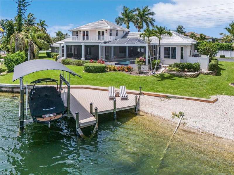 Back of house featuring 7500# boat lift, a balcony, a water view with private sandy beach