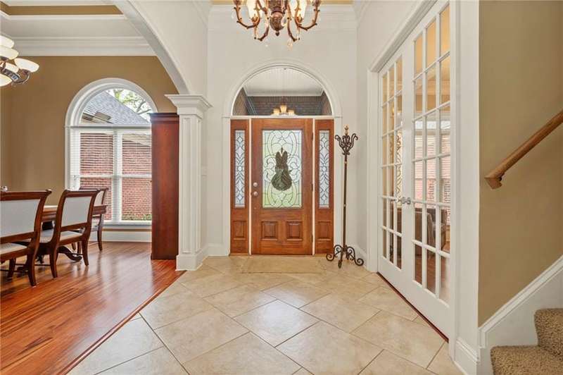 Entrance foyer featuring ornamental molding, arched walkways, baseboards, stairs, and a notable chandelier
