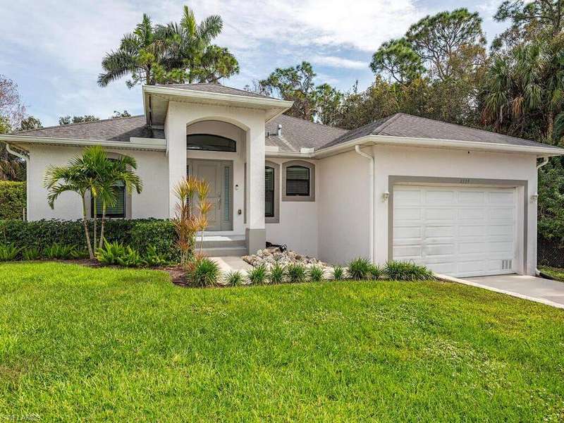 View of front of home featuring a garage, driveway, a front yard, and stucco siding