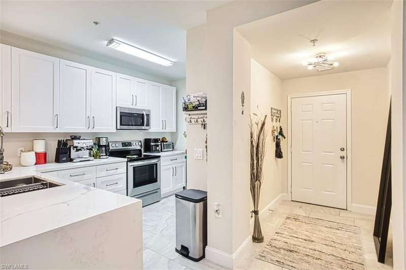 Kitchen with white cabinets, appliances with stainless steel finishes, and light stone counters
