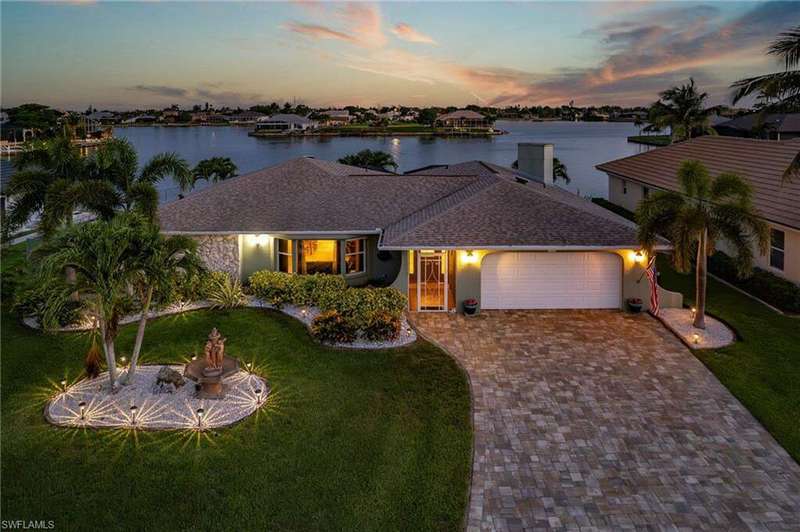 View of front of home with a garage, a front yard, decorative driveway, and a water view