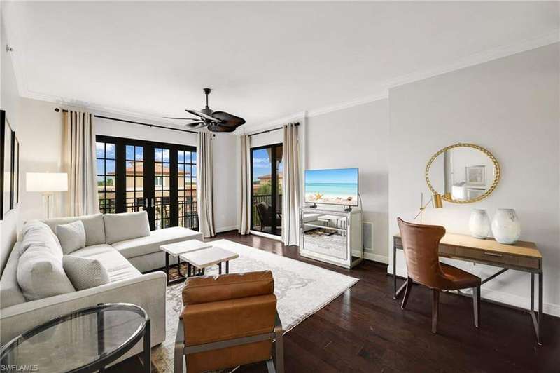 Living room with crown molding, dark wood-style flooring, and a ceiling fan