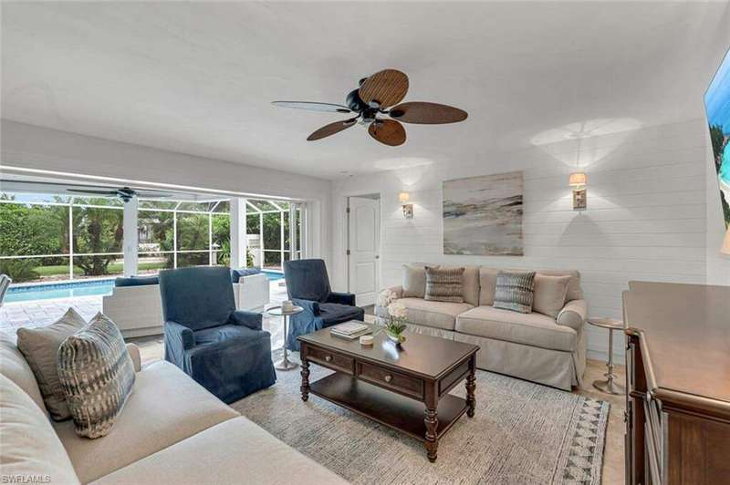 Living room featuring ceiling fan, wood walls, light hardwood / wood-style floors, and a wealth of natural light