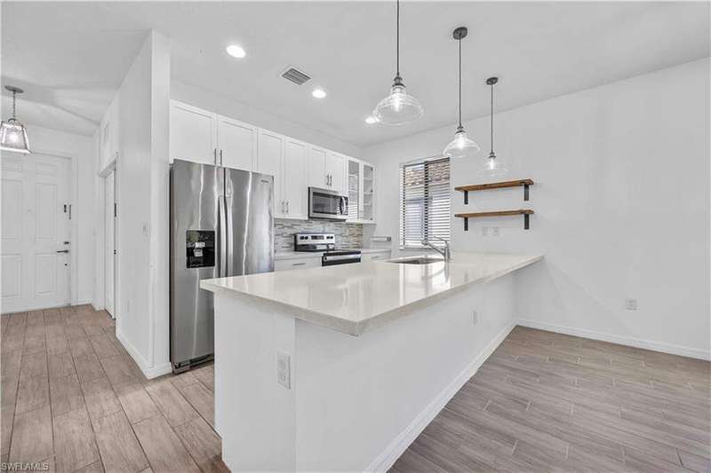 Kitchen featuring glass insert cabinets, white cabinetry, open shelves, appliances with stainless steel finishes, and light stone countertops