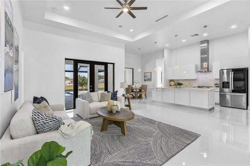 Living room featuring a high ceiling, ceiling fan, light tile patterned floors, recessed lighting, and a tray ceiling