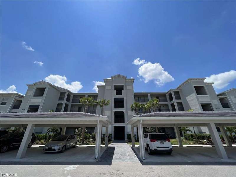View of apartment building / complex featuring covered parking