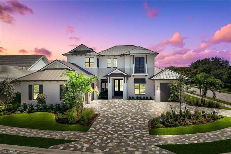 Modern inspired farmhouse with a standing seam roof, metal roof, a garage, stucco siding, and decorative driveway