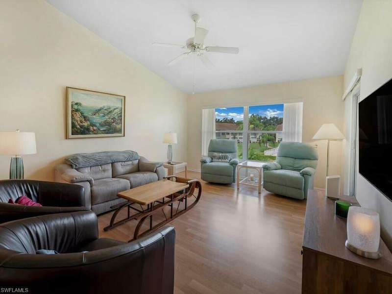 Living room with ceiling fan, vaulted ceiling, and wood-type flooring