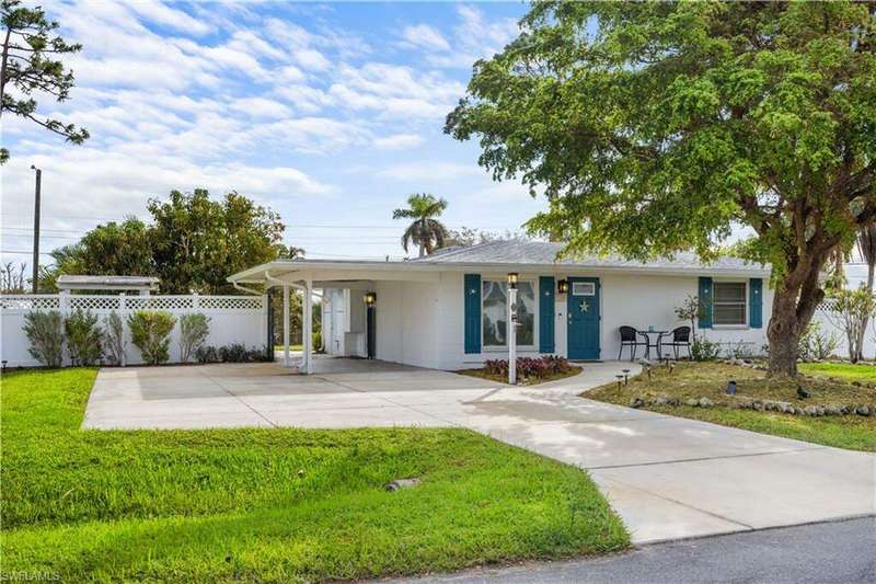 Single story home with a front yard, covered porch, and a carport