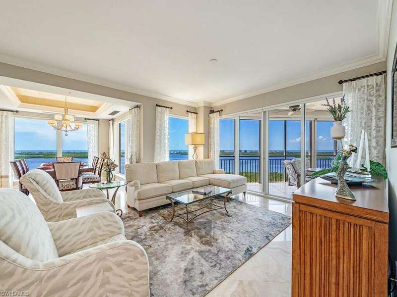 Living room featuring plenty of natural light, a water view, a chandelier, and ornamental molding