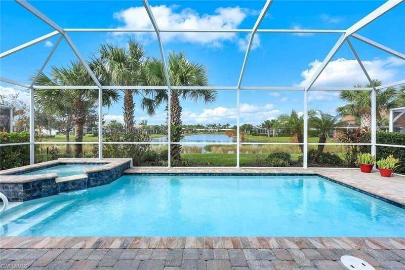 View of pool with an in ground hot tub, a water view, and glass enclosure