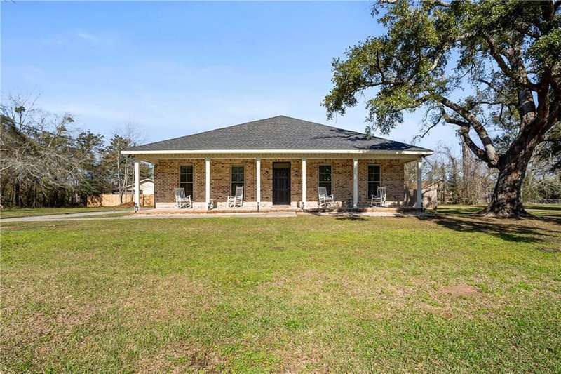 View of front of home featuring covered porch, a front lawn, a shingled roof, and brick siding