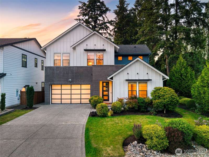 This stunning modern farmhouse blends crisp architectural lines with warm, inviting interiors, all set against a backdrop of lush evergreens. Featuring a striking brick and board-and-batten exterior, manicured landscaping, and a glowing welcome through ov