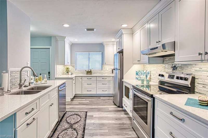 Kitchen featuring appliances with stainless steel finishes, under cabinet range hood, light stone countertops, recessed lighting, and light wood finished floors