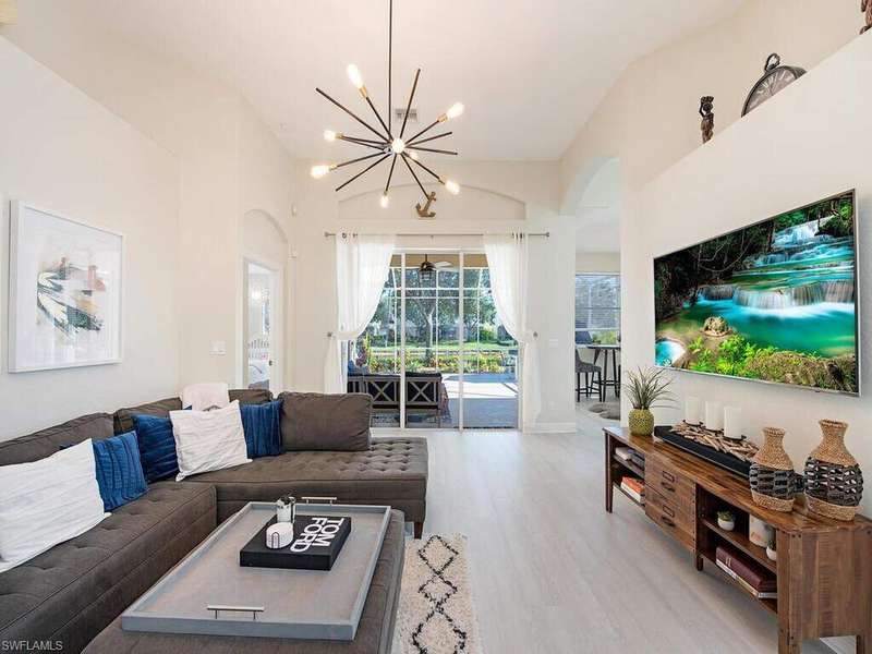 Living room with arched walkways, light wood-type flooring, and a chandelier