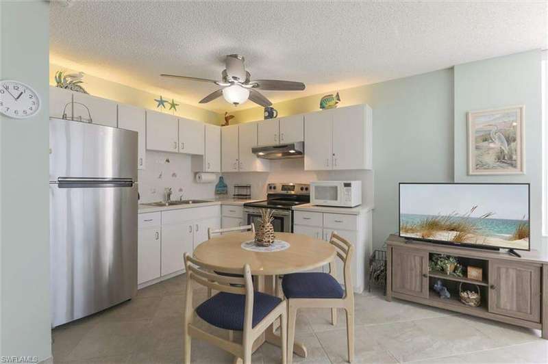 Kitchen with stainless steel appliances, sink, light tile patterned floors, a textured ceiling, and ceiling fan