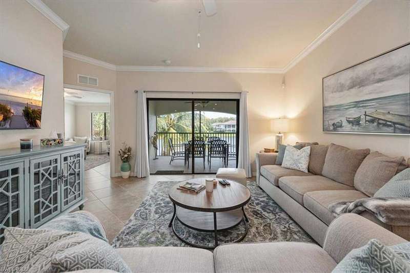 Living room featuring light tile patterned floors, ornamental molding, and ceiling fan