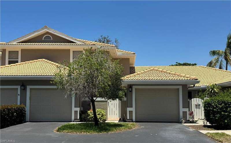 View of front of home with stucco siding, a tile roof, and a garage