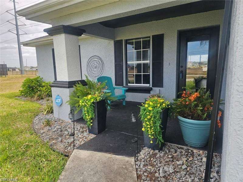Property entrance with a yard, covered porch, and stucco siding
