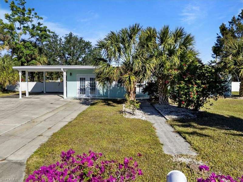 View of front of property featuring french doors, a carport, and a front lawn