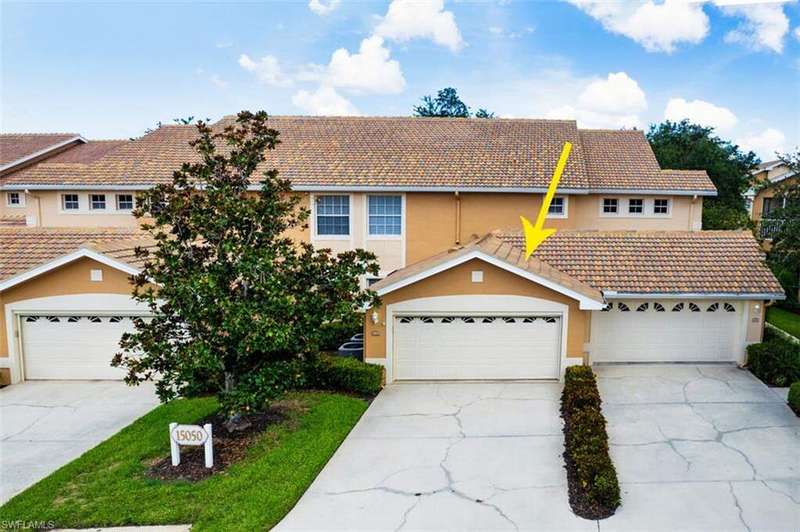 View of front facade with a tiled roof, stucco siding, and concrete driveway