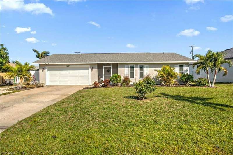 Ranch-style house featuring a garage and a front lawn