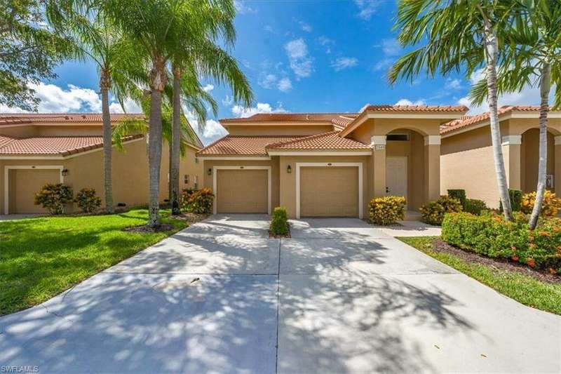 Mediterranean / spanish coach home with a garage and a front lawn