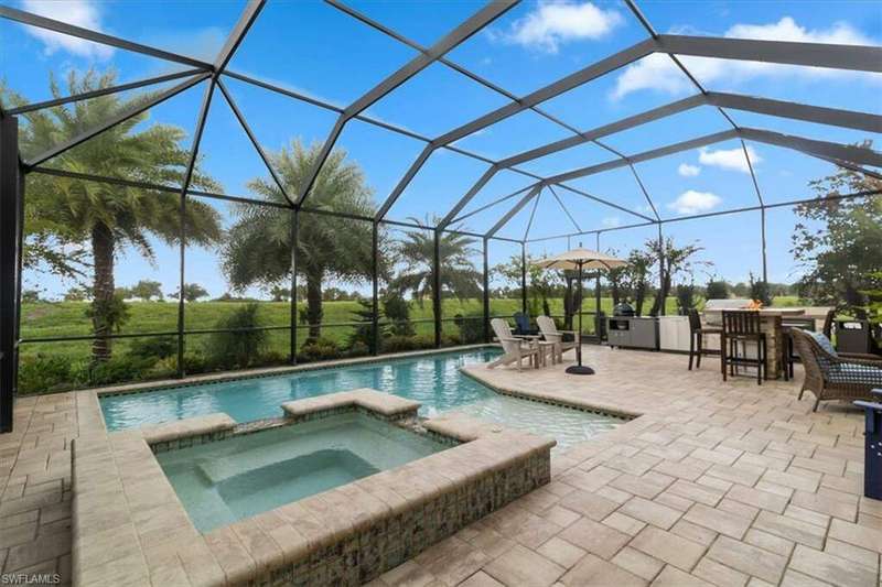 View of swimming pool with an in ground hot tub, glass enclosure, a bar, and a patio area