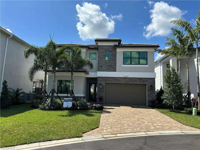 View of front of home with a garage, a front lawn, and cooling unit