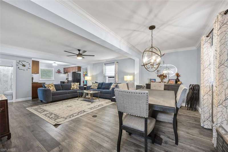 View of dining space and living room featuring vinyl flooring and crown molding