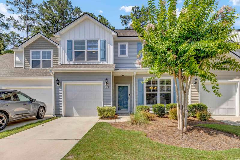 View of front facade with concrete driveway, board