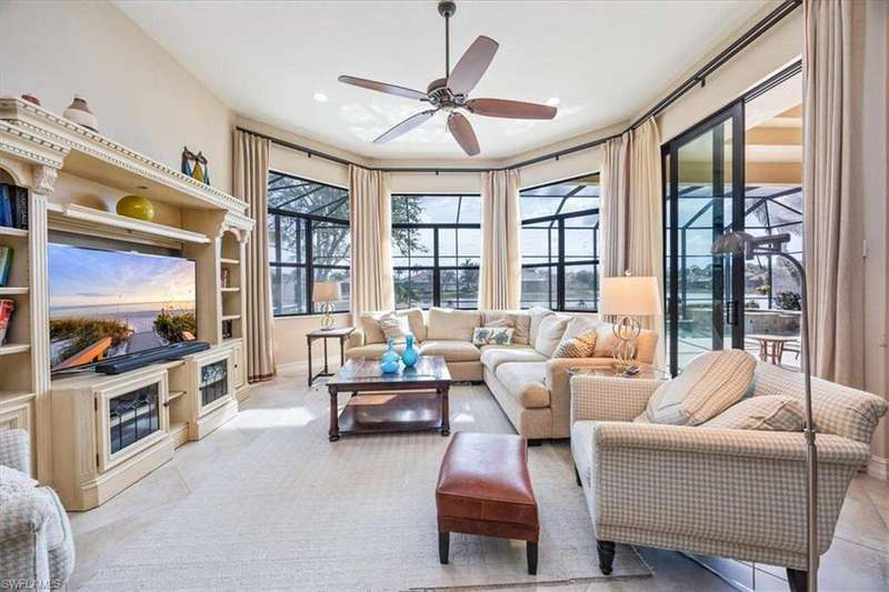 Pool at dusk featuring a lanai, a water view, a patio area, and a pool with connected hot tub