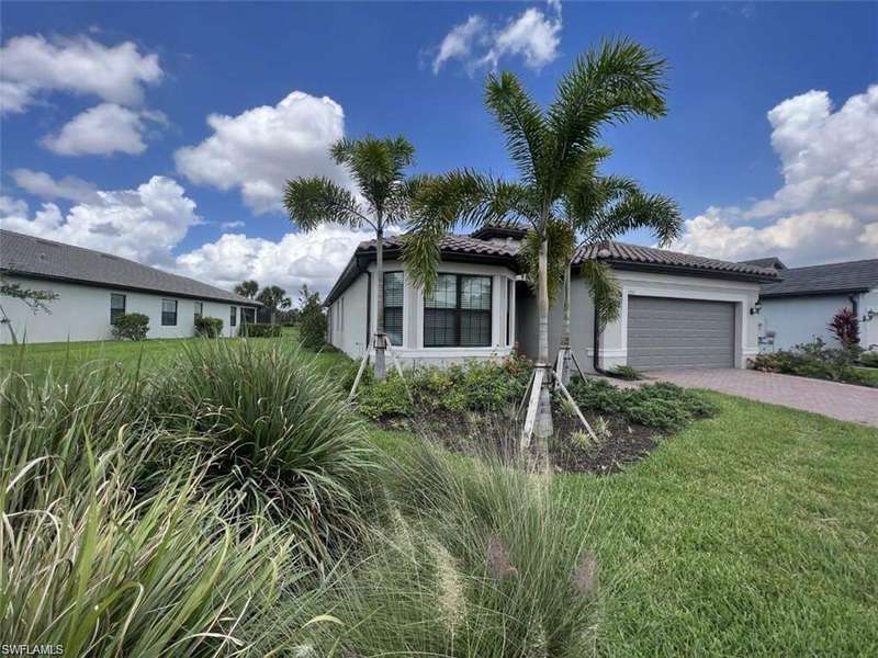 View of front facade with decorative driveway, stucco siding, a front yard, an attached garage, and a tiled roof