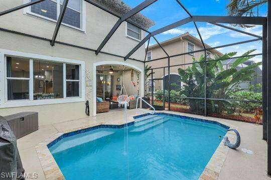 View of swimming pool featuring a lanai, a patio area, and ceiling fan
