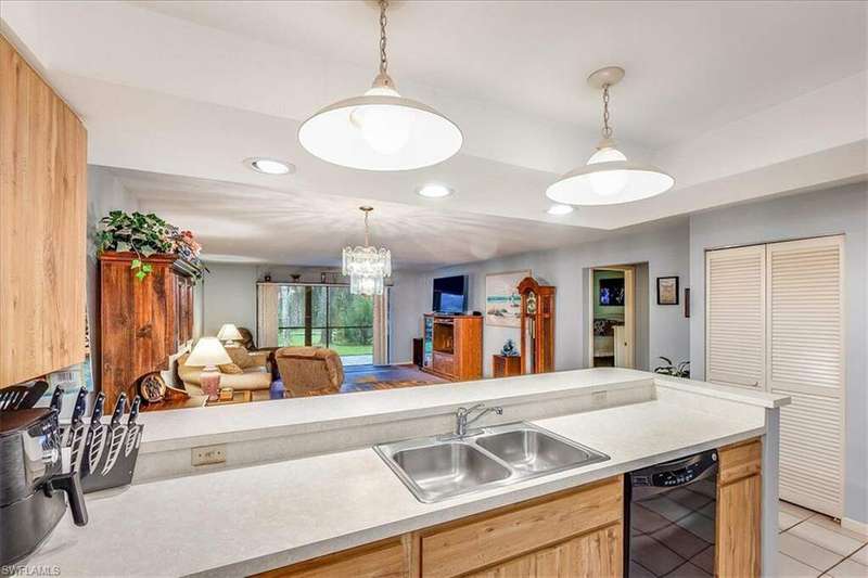 Kitchen with black appliances, stacked washer / drying machine, sink, ceiling fan, and light tile flooring