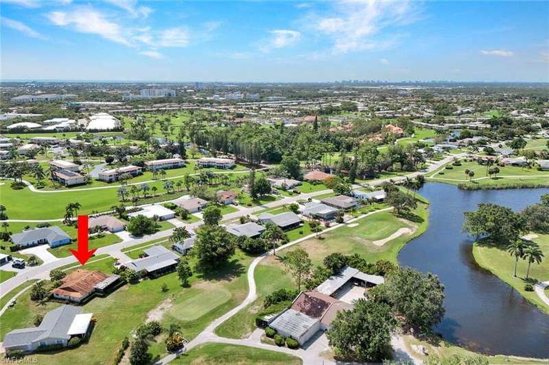 Aerial overview of property's location featuring a large body of water, a golf club, and nearby suburban area