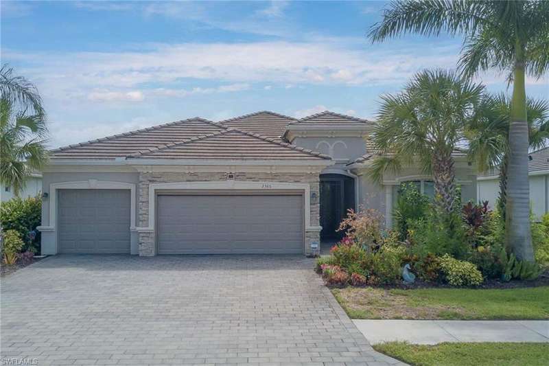 Mediterranean / spanish-style home with an attached garage, stone siding, decorative driveway, and a tile roof