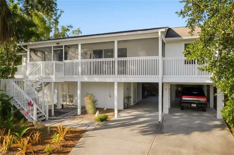 Rear view of house with a carport, stairway, a sunroom, and driveway