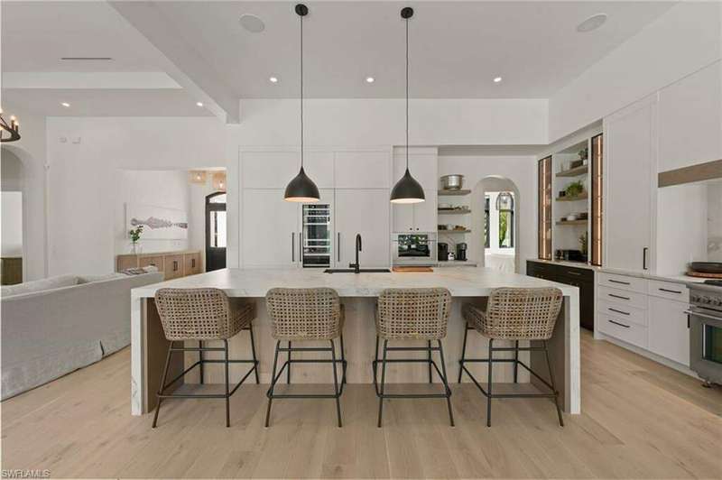 Kitchen with white cabinetry, a large island, a breakfast bar, and hanging light fixtures