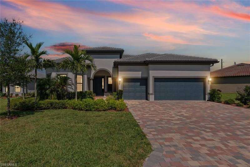 Mediterranean / spanish home featuring a garage, driveway, a front lawn, and stucco siding
