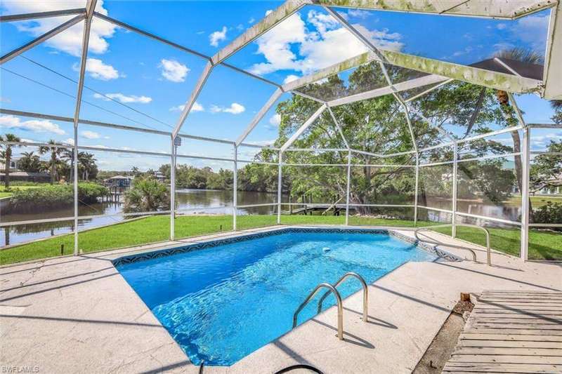 Pool with screen enclosure, a patio area, a water view, and a lawn