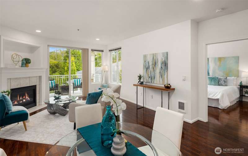 Open floor-plan living room with gas fireplace looking out over covered patio with greenbelt views.