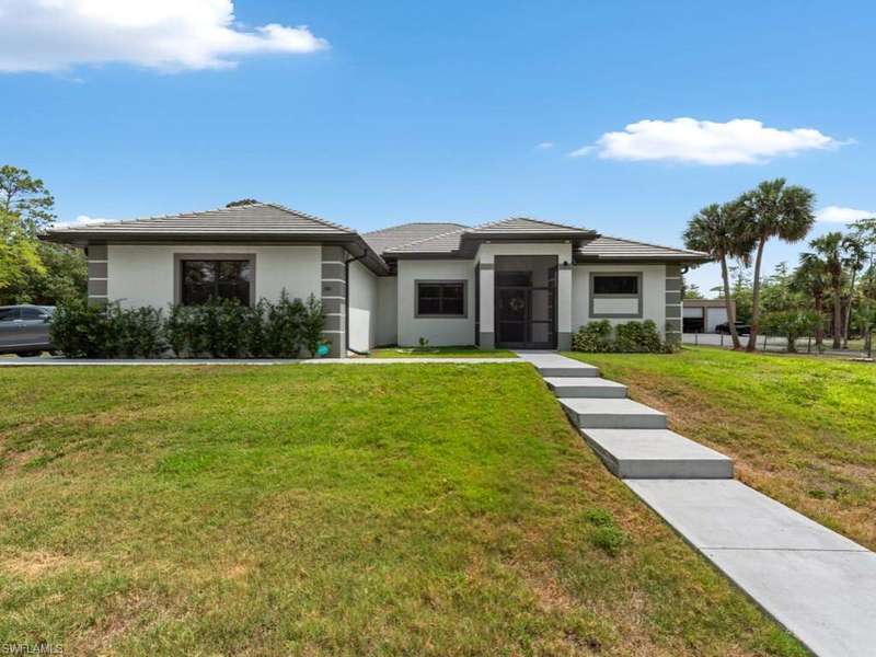 Prairie-style home featuring a tile roof, stucco siding, and a front yard